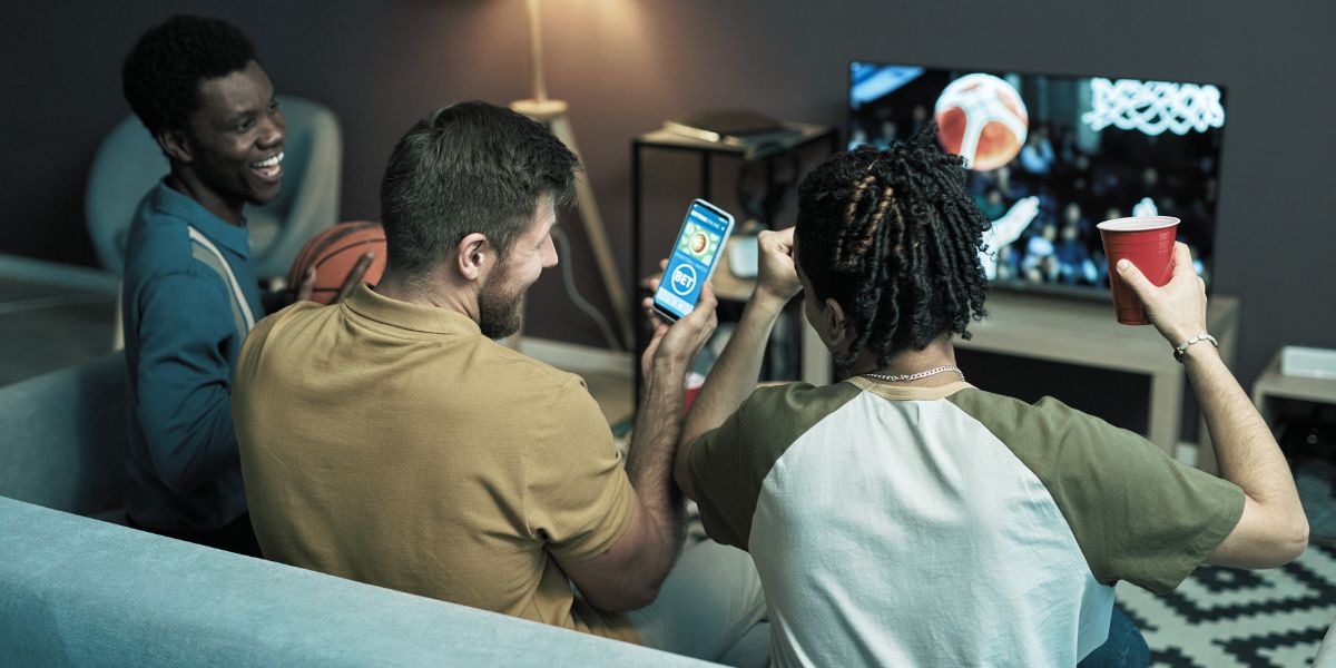 Amis qui regardent et parient en live devant un match de basket - le bon parieur